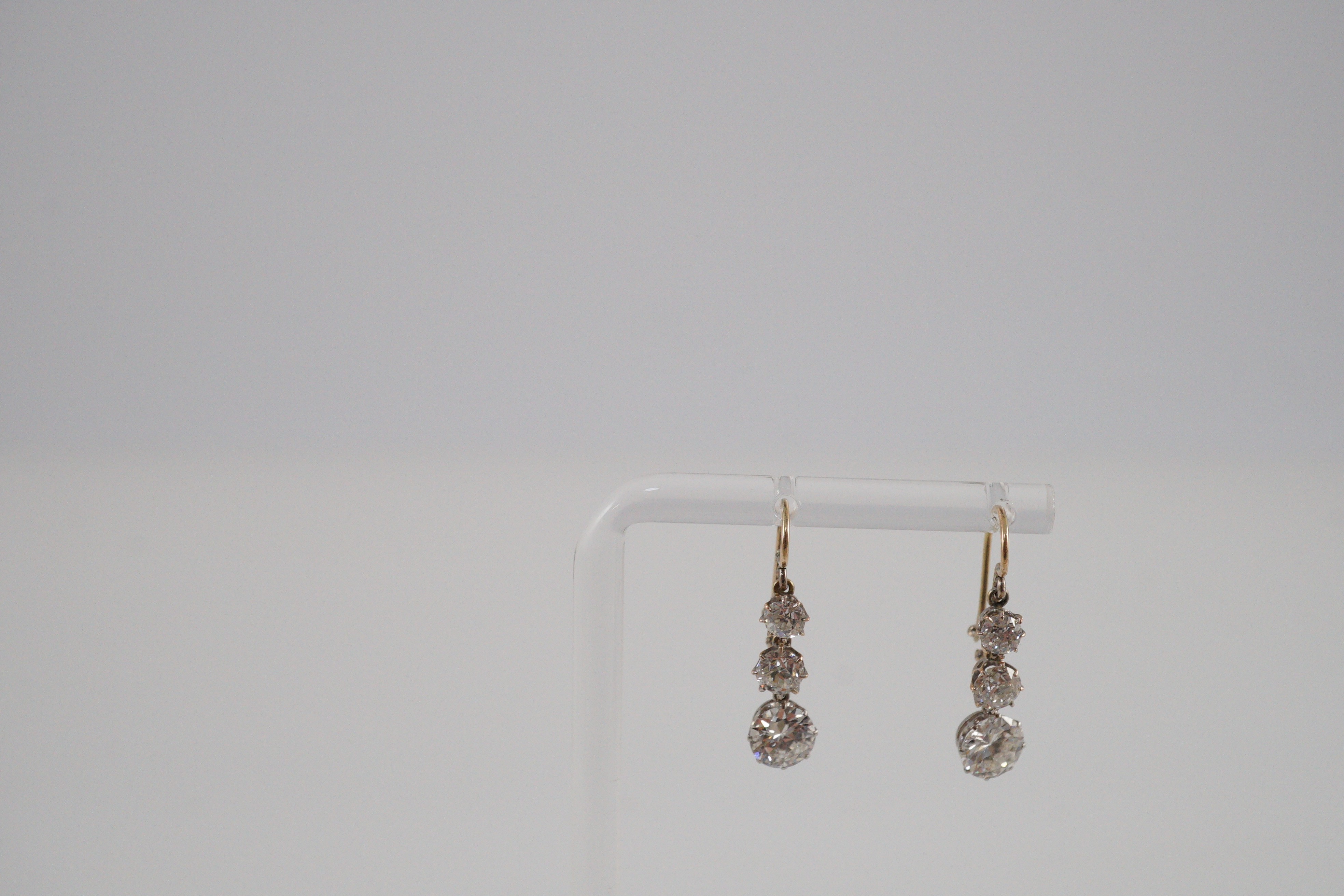 A pair of early to mid 20th century gold, platinum and graduated three stone diamond set drop earrings